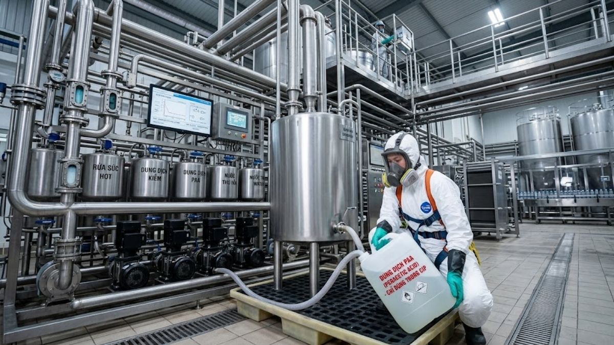 Nhân viên kỹ thuật mặc đồ bảo hộ đang châm dung dịch PAA vào hệ thống CIP nhà máy